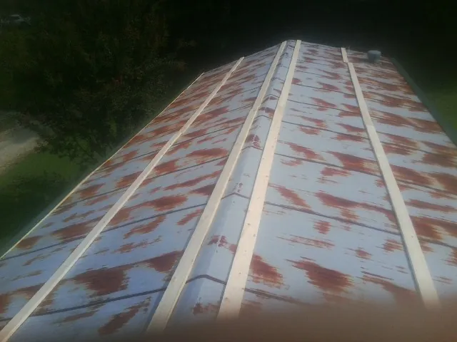 Rusted metal roof panels with new wood purlins before replacement — Storm Damage Roof Repair in Amherst by Roofing Brothers